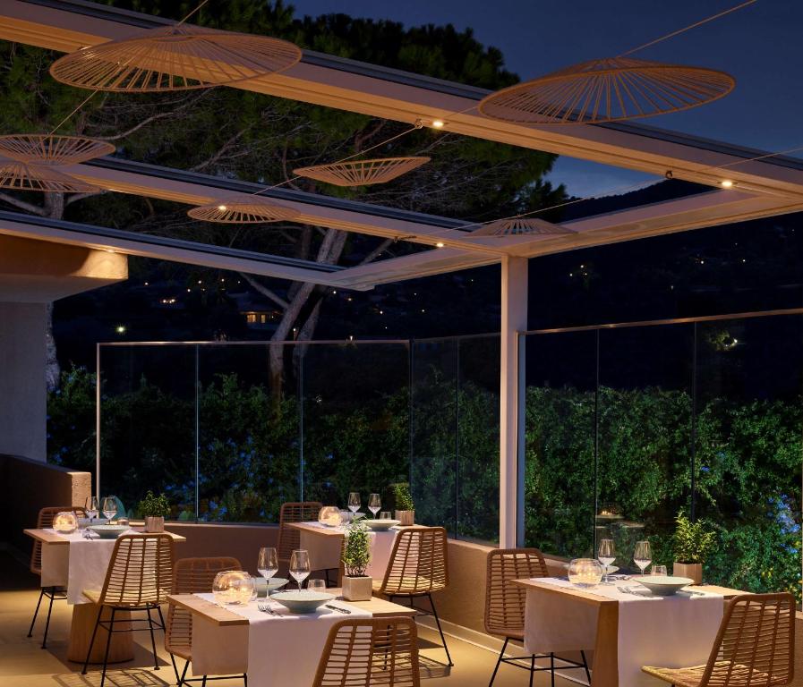 a restaurant with white tables and chairs and umbrellas at Conrad Chia Laguna Sardinia in Chia