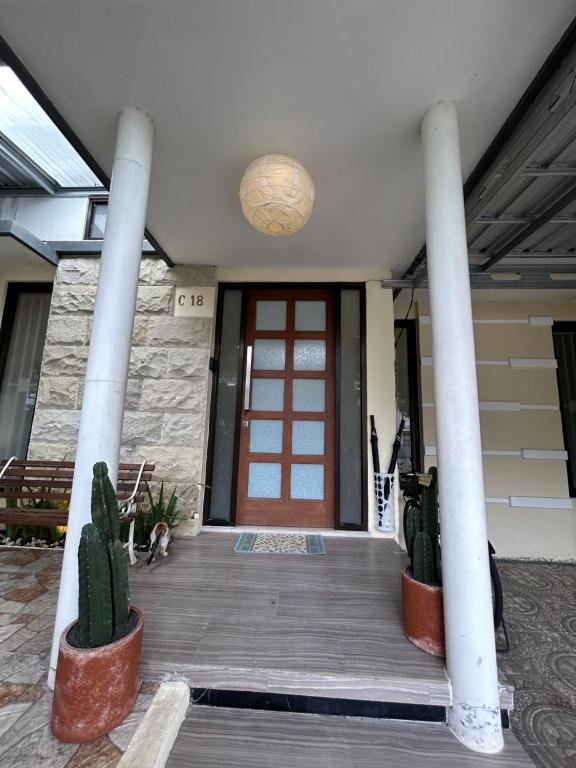 a front door of a building with cactuses on a wooden porch at Dea's House Homestay in Blimbing