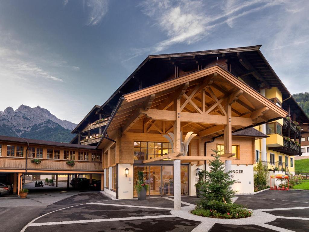 a lodge with a large building with mountains in the background at Waidringer Hof 4 Sterne Superior in Waidring
