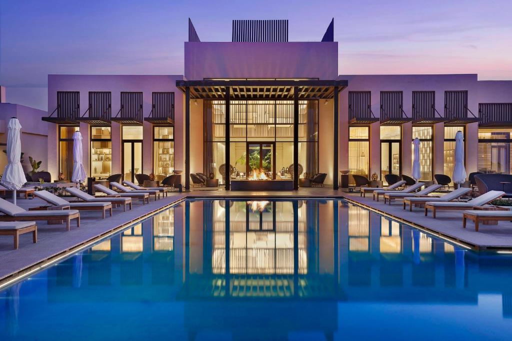 a hotel swimming pool with lounge chairs in front of a building at Conrad Rabat Arzana in Rabat
