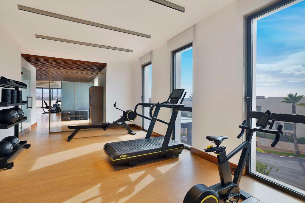 a gym with treadmills and ellipticals in a room with windows at Conrad Rabat Arzana in Rabat