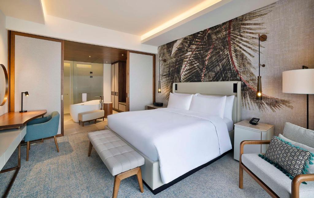 a bedroom with a large white bed and a desk at Conrad Rabat Arzana in Rabat