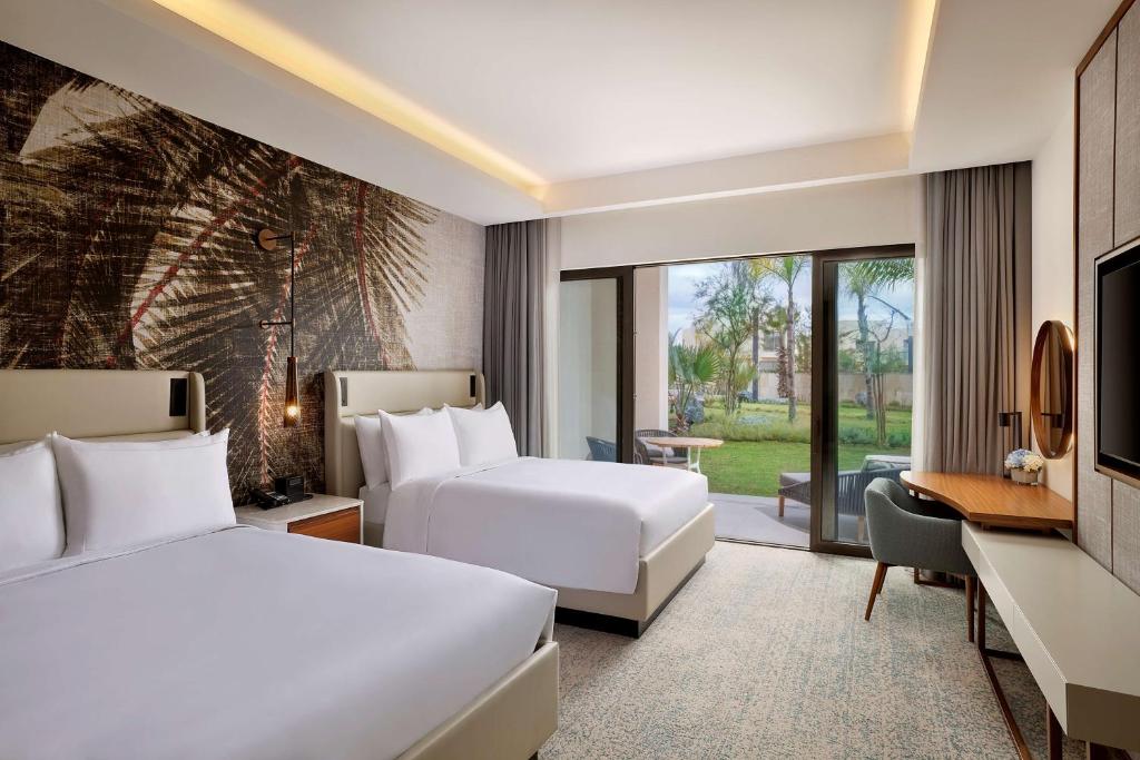 a hotel room with two beds and a desk at Conrad Rabat Arzana in Rabat