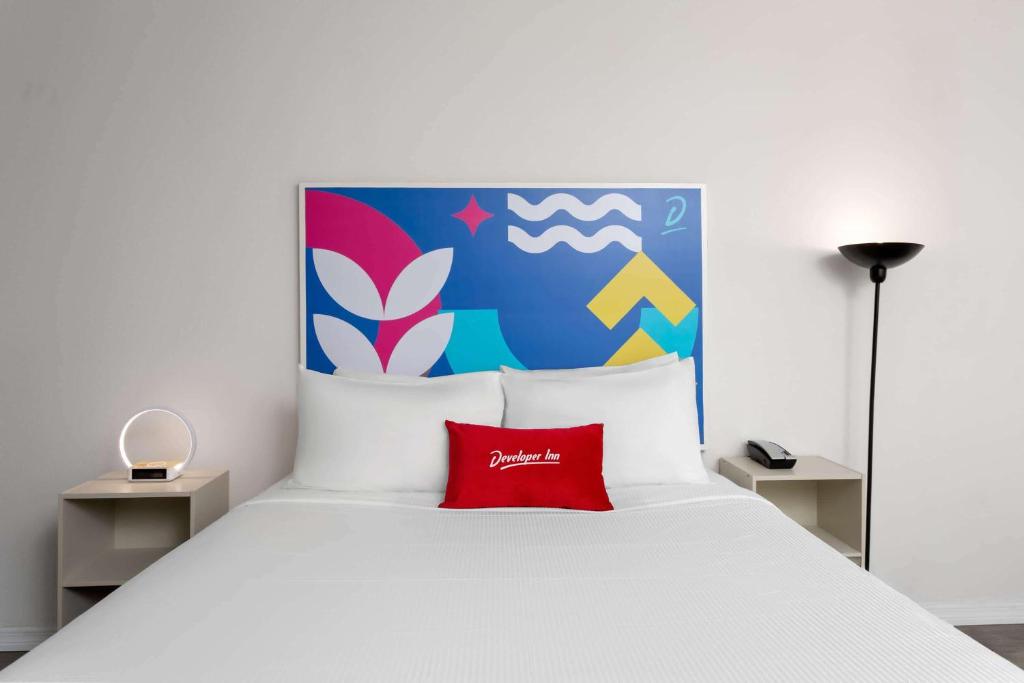 a bedroom with a white bed with a red pillow at Baymont by Wyndham Orlando North Millenia in Orlando