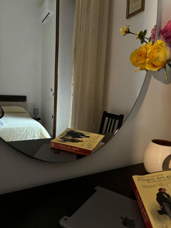 a mirror on a desk with a book and a bed at Station Comfort House in Pagani