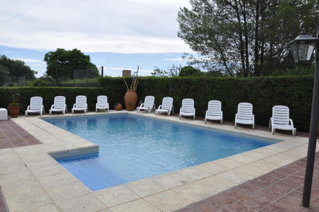 a swimming pool with chairs and a bunch of chairs at Hotel de la Cañada Mina Clavero in Mina Clavero