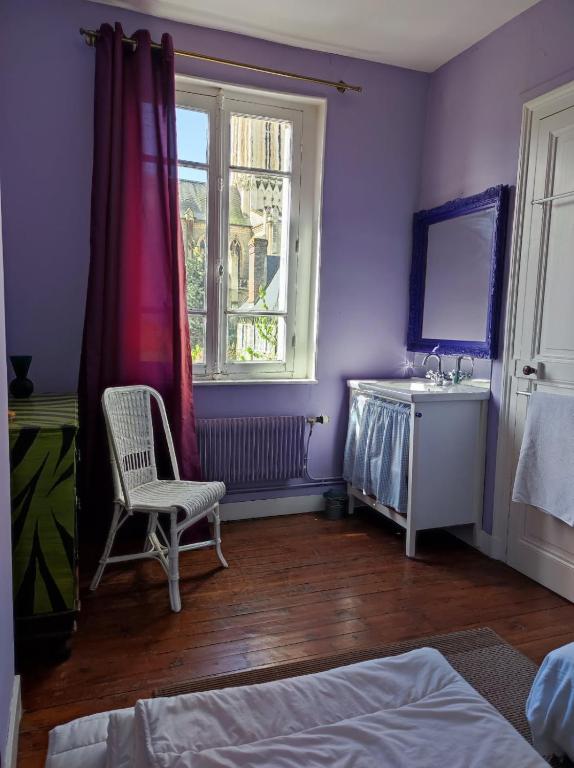 - une chambre avec des murs violets, une chaise et une fenêtre dans l'établissement Charmante villa, à Villers-sur-Mer