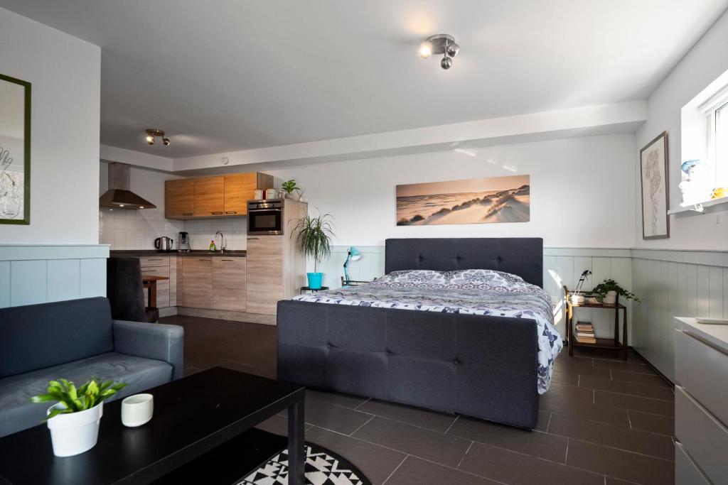 a bedroom with a bed and a couch and a table at Co's Duyne - Beautiful studio near the dunes of Callantsoog in Callantsoog