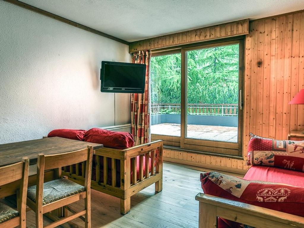 - un salon doté d'une table et d'une télévision dans l'établissement Appartement 80 m², 8 pers., 4 ch., centre Val d'Isère, terrasse, parking, proche pistes - FR-1-519-20, à Val dʼIsère