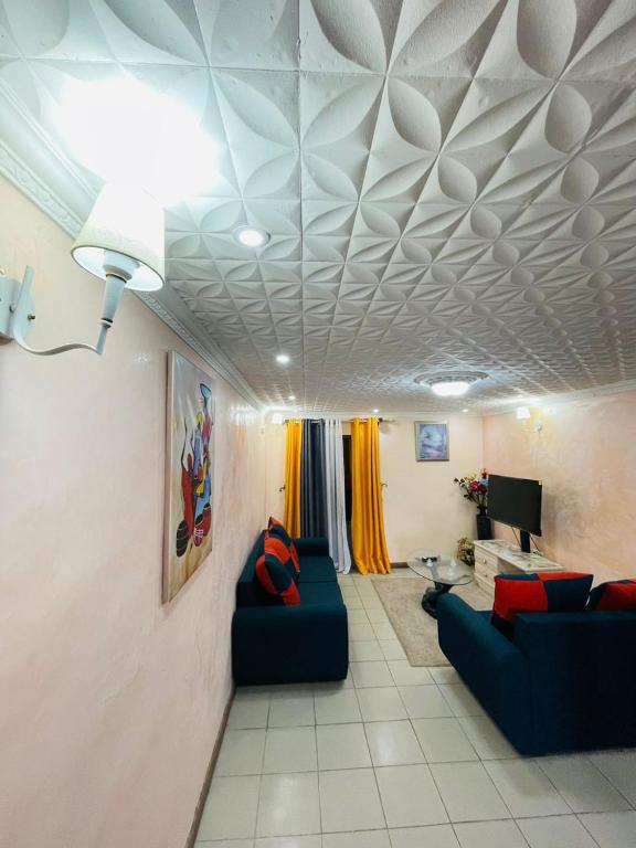 a living room with two blue couches and a ceiling at Black Diamond Appartements in Kribi