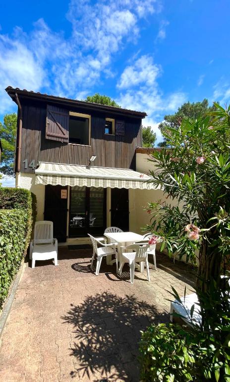 un patio avec une table et des chaises devant une maison dans l'établissement Lou Hapchot, à Lacanau