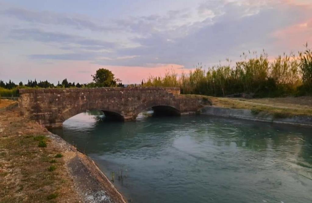 un pont en pierre sur une rivière avec de l'eau dans l'établissement Le Refuge des Cigalons, à Cavaillon