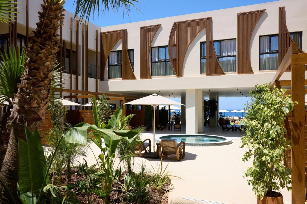 a building with a courtyard with a swimming pool at Isla Brown Chania Resort, Curio Collection by Hilton in Stavros