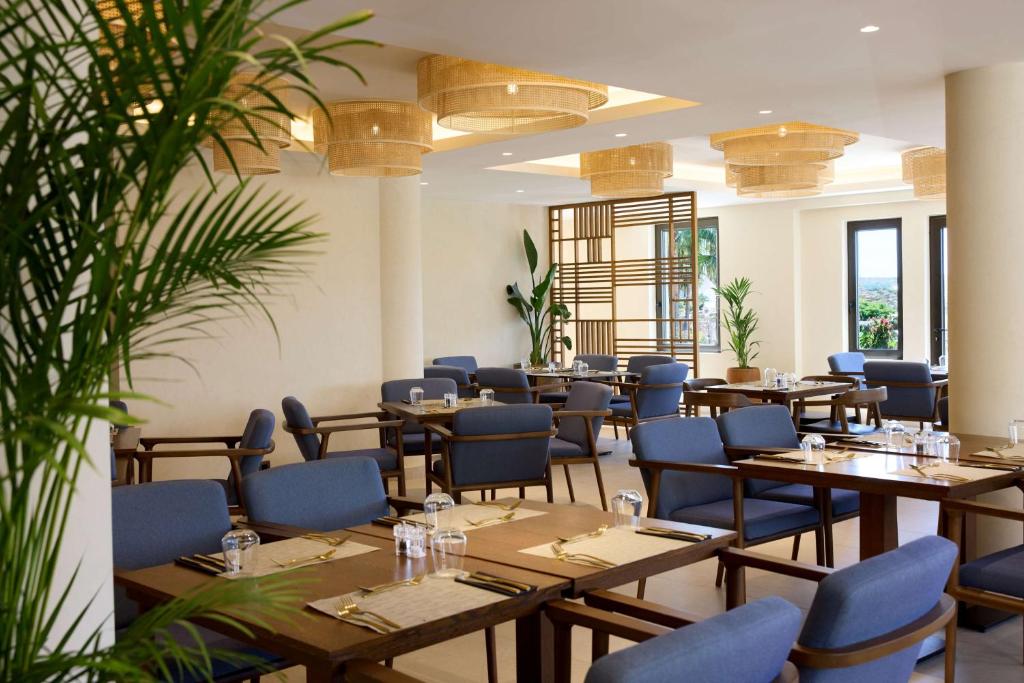 a restaurant with wooden tables and blue chairs at Isla Brown Chania Resort, Curio Collection by Hilton in Stavros