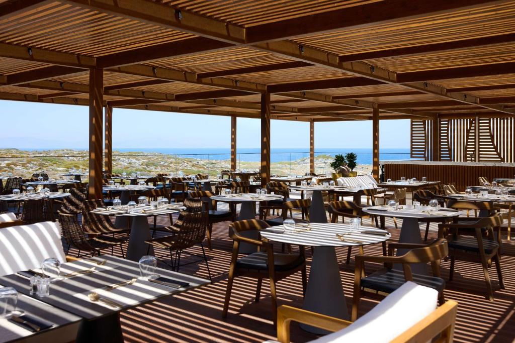 a restaurant with tables and chairs on a deck at Isla Brown Chania Resort, Curio Collection by Hilton in Stavros