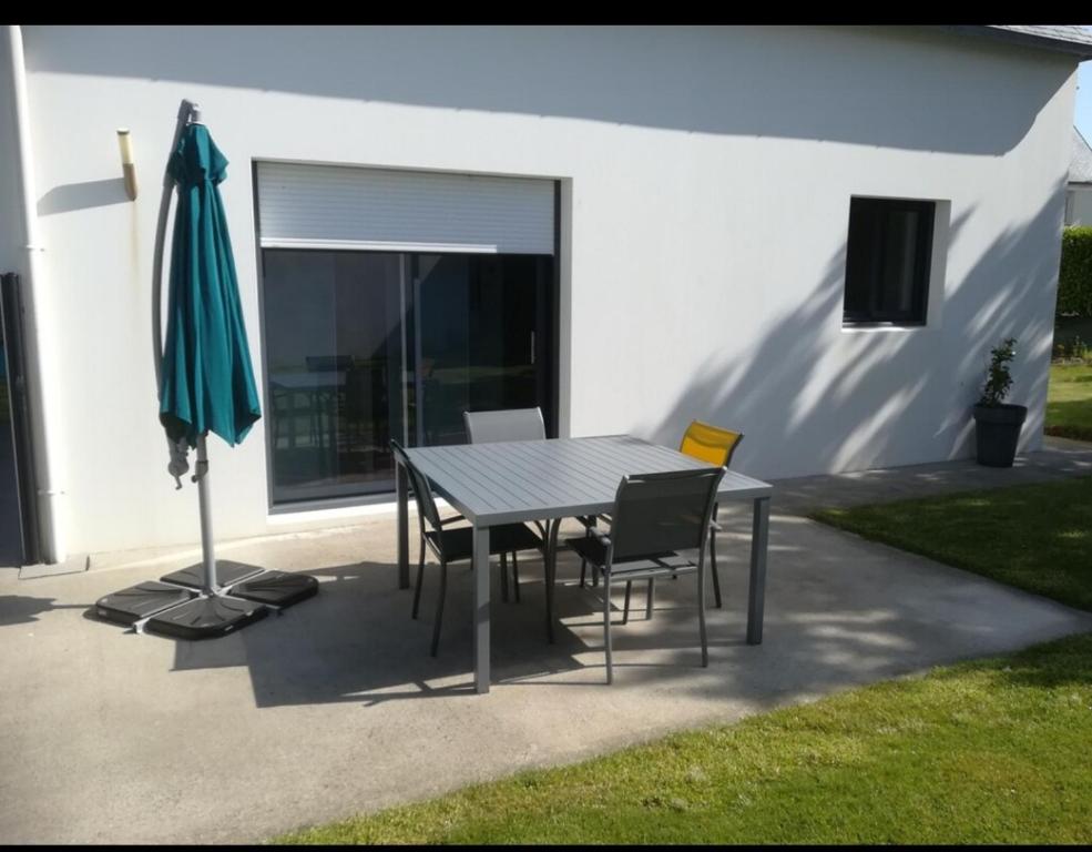 - une table, des chaises et un parasol sur la terrasse dans l'établissement Meublé 3 étoiles Les Capucines, à Plouescat