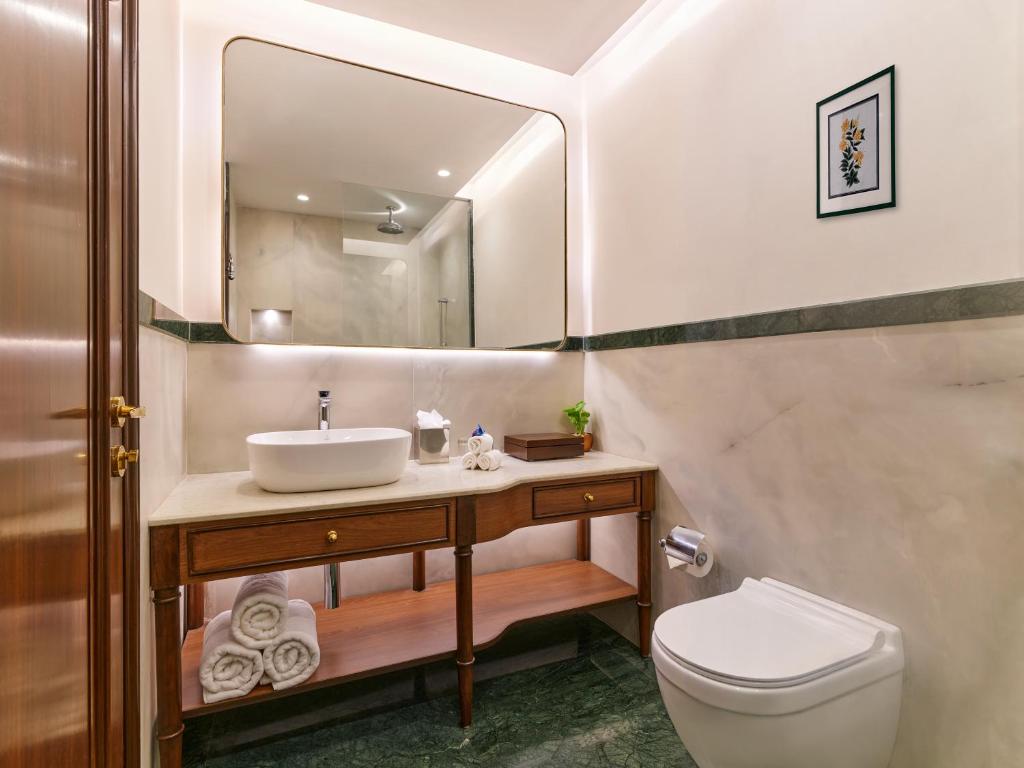 a bathroom with a sink and a toilet and a mirror at The Ummed Ahmedabad Airport in Ahmedabad