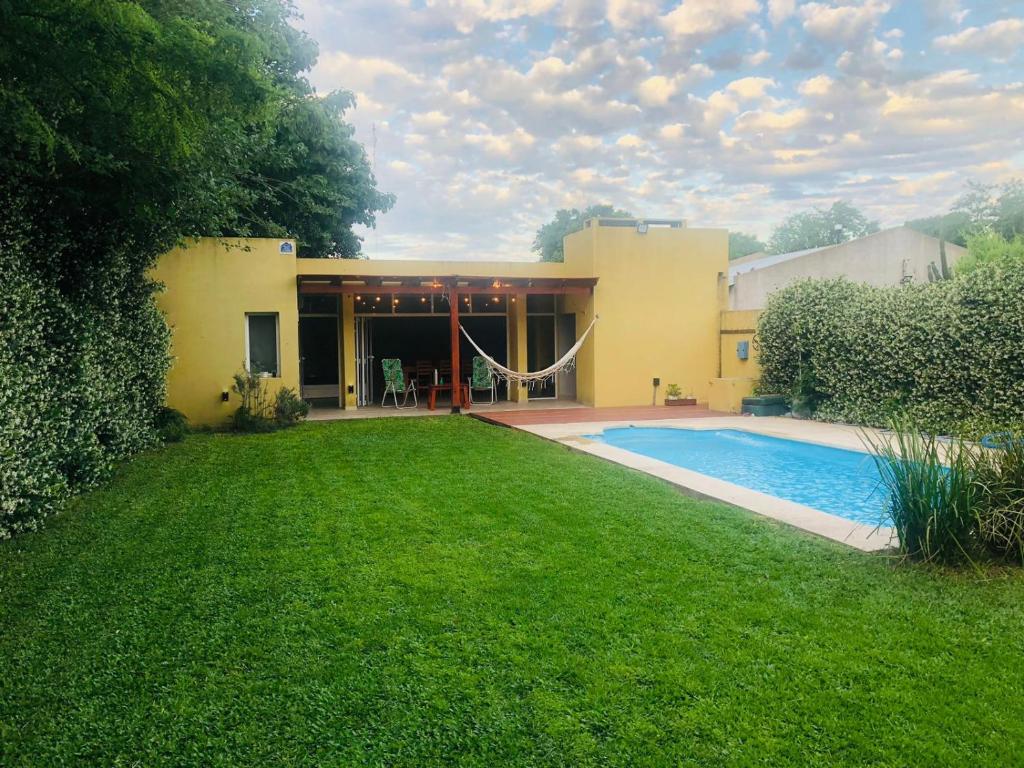 a house with a swimming pool in front of a yard at La quinta de los peques in Los Toldos