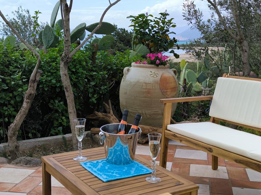 a table with glasses and a vase on a patio at Splendida villa in riva al mare in Orosei