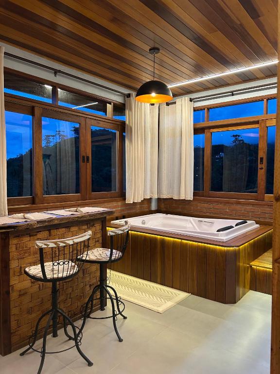 a jacuzzi tub in a room with chairs and a table at Chalés Amantes da Montanha - Visconde de Mauá in Bocaina de Minas