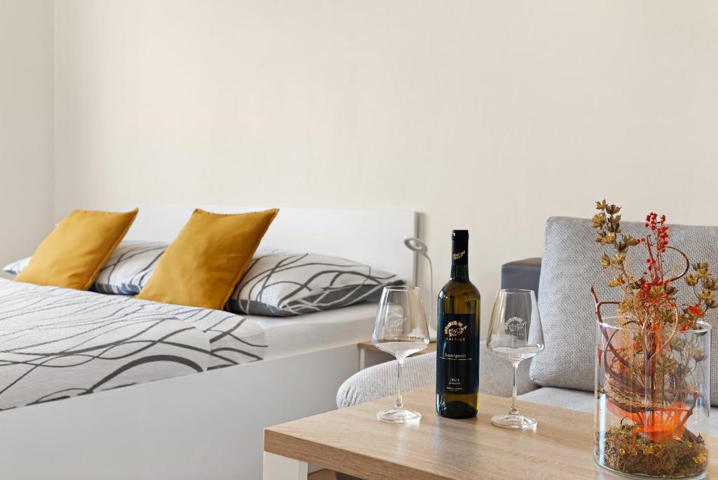 a table with a bottle of wine and glasses on a bed at Nad Šťastným sklepem in Valtice