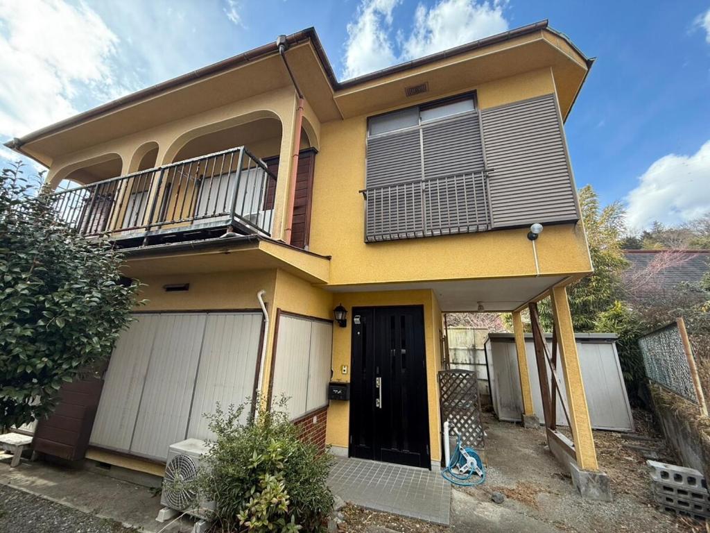 a yellow house with a balcony and a black door at SUWAHouse in Gora
