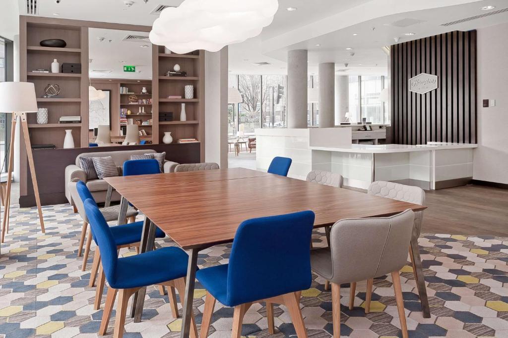 a dining room with a wooden table and blue chairs at Hampton by Hilton London Waterloo in London