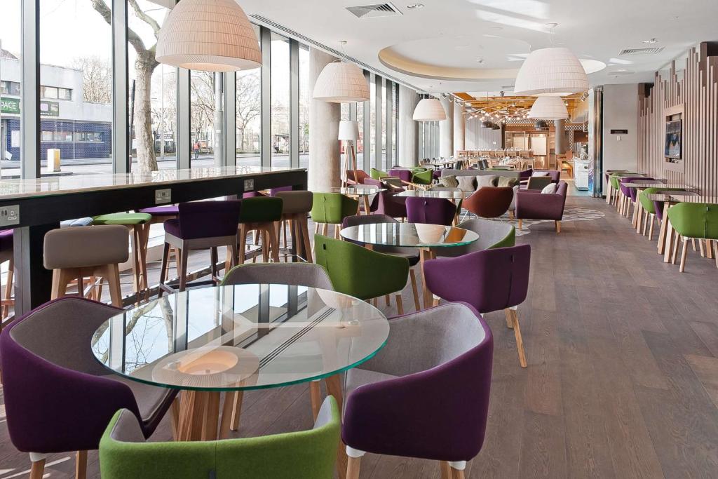 a restaurant with tables and chairs and windows at Hampton by Hilton London Waterloo in London
