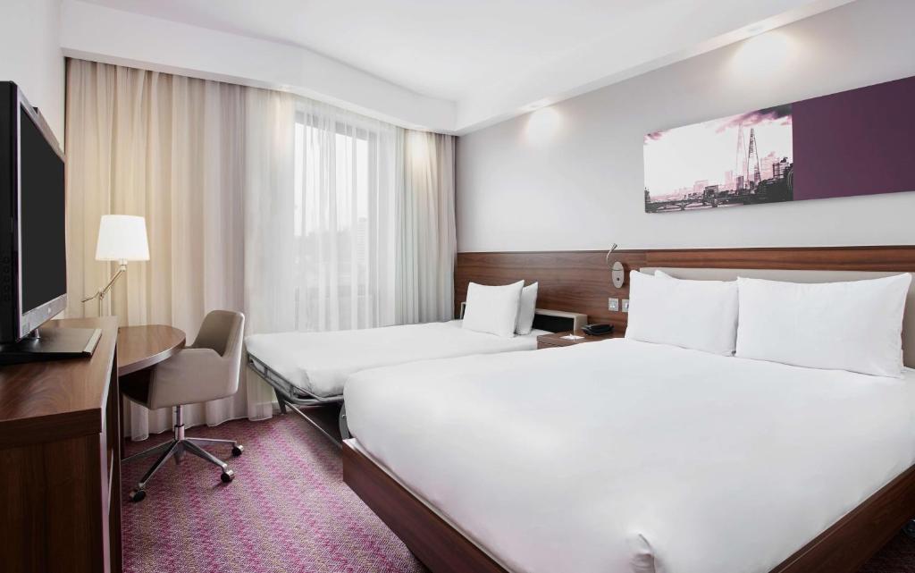 a hotel room with two beds and a desk at Hampton by Hilton London Waterloo in London