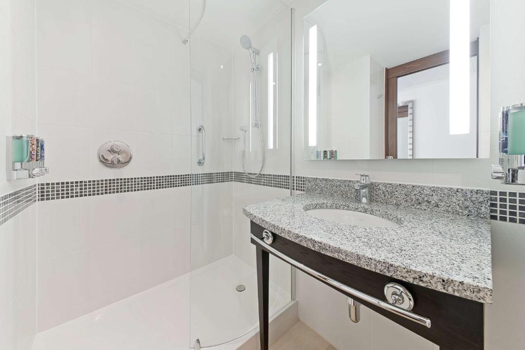 a white bathroom with a sink and a mirror at Hampton by Hilton London Waterloo in London