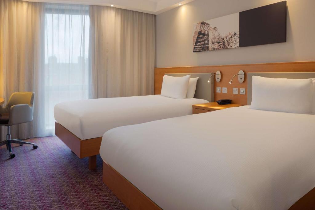 a hotel room with two beds and a chair at Hampton by Hilton London Waterloo in London