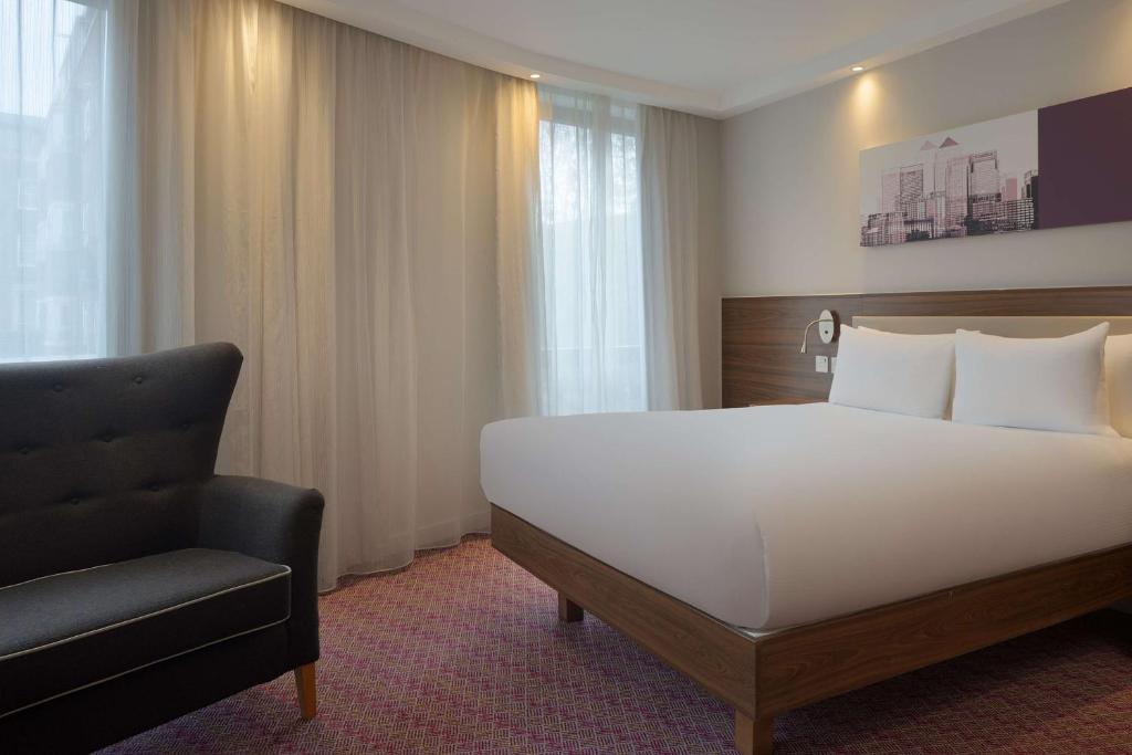 a bedroom with a large white bed and a chair at Hampton by Hilton London Waterloo in London