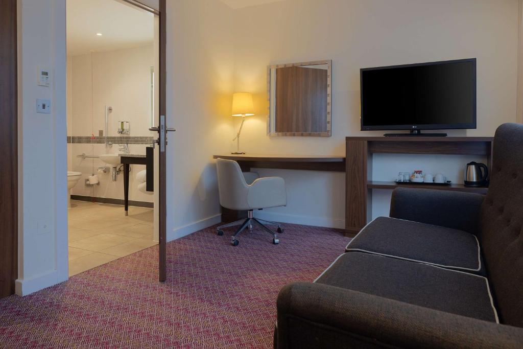 a hotel room with a couch and a desk with a television at Hampton by Hilton London Waterloo in London