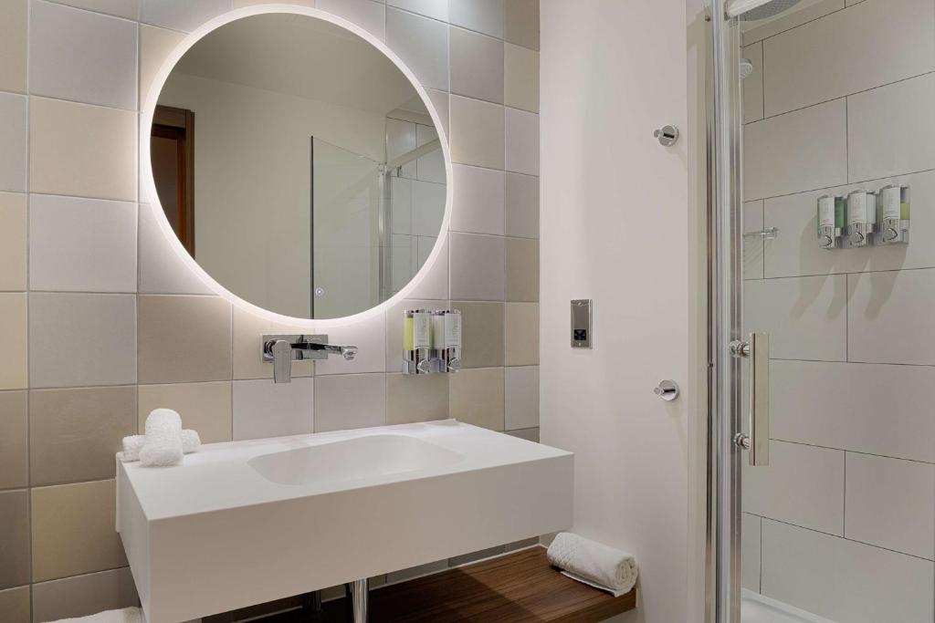 a white bathroom with a sink and a mirror at Hampton by Hilton London Waterloo in London