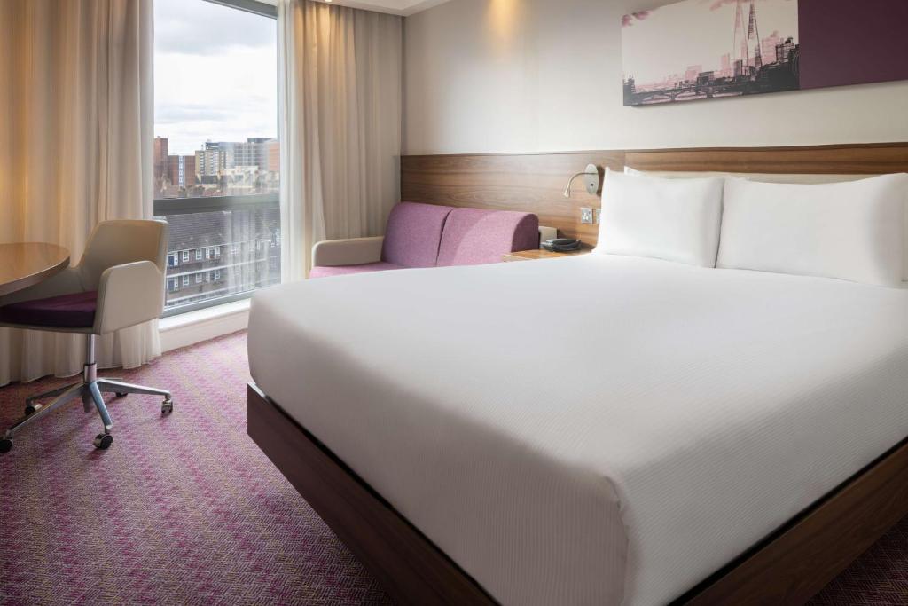 a hotel room with a bed and a desk and a window at Hampton by Hilton London Waterloo in London