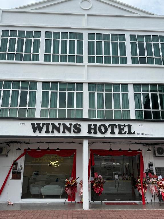 彭亨Winn's Hotel Bentong的一座白色的建筑,上面标有酒店标志