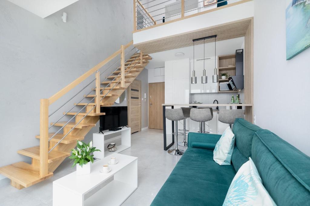 a living room with a green couch and a staircase at Apartament Holiday Pelican in Rewal