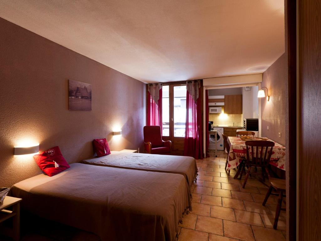 une chambre d'hôtel avec deux lits, une table et des chaises dans l'établissement Charmant studio pour 4 pers. avec balcon, parking et wifi, à deux pas des Thermes et du centre village - FR-1-512-212, à Brides-les-Bains