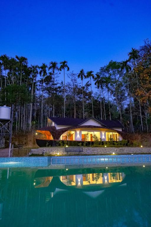 a house with a swimming pool at night at Ginberry Holidays in Wayanad