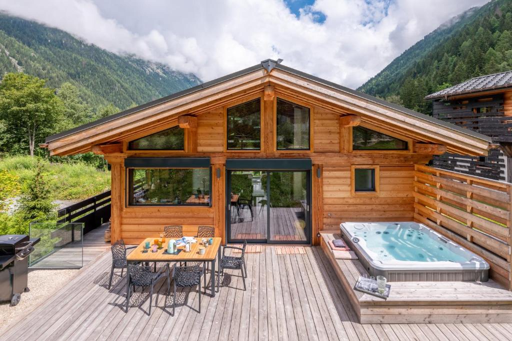 une cabane en rondins avec un bain à remous sur une terrasse dans l'établissement Chalet Seven Summits - Pool - Sauna - Jacuzzi - By Cozee Rentals, à Chamonix-Mont-Blanc
