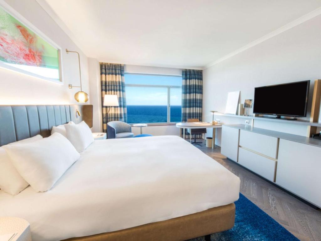 a hotel room with a large bed and a television at Hilton Diagonal Mar Barcelona in Barcelona