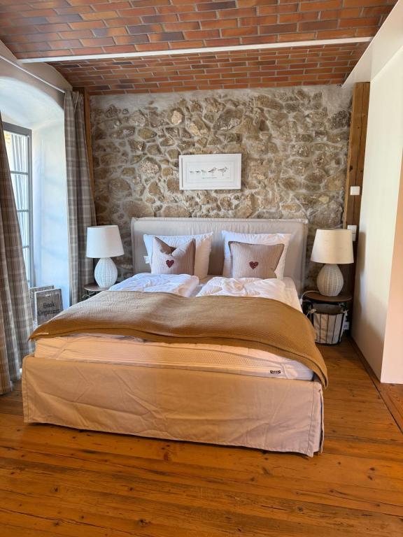 ein Schlafzimmer mit einem großen Bett mit einer Steinwand in der Unterkunft Landgut Mosch in Radeburg