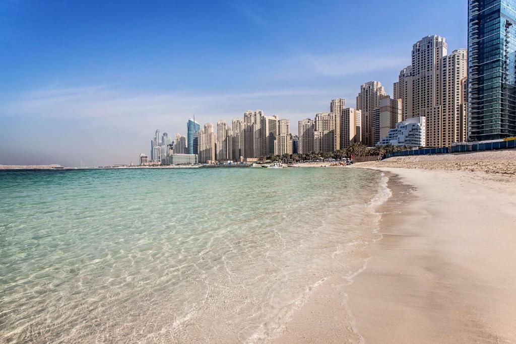 a beach in front of a city with tall buildings at Hilton Dubai The Walk in Dubai