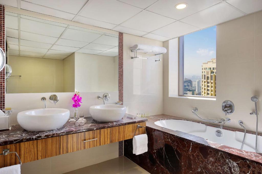 a bathroom with two sinks and a large mirror at Hilton Dubai The Walk in Dubai