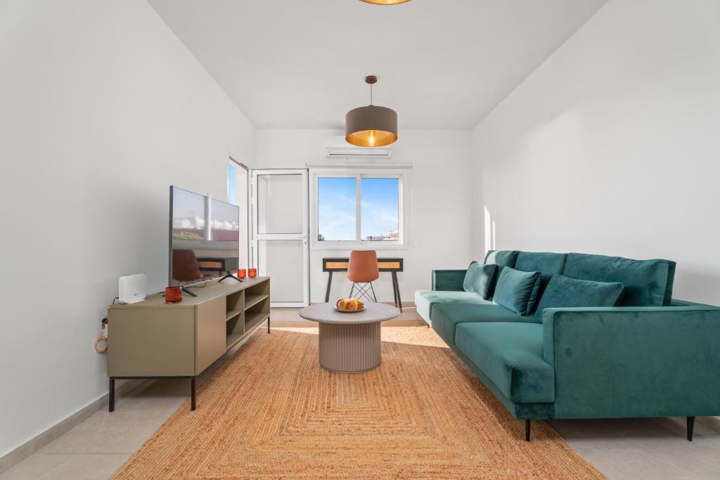 Modern seaview apartment in the heart of Agia Napa في أيا نابا: غرفة معيشة مع أريكة زرقاء وطاولة