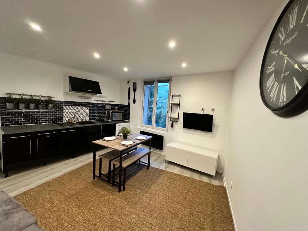 - un salon avec une table et une horloge murale dans l'établissement Le cosy de la gare 5, à Nazelles-Négron