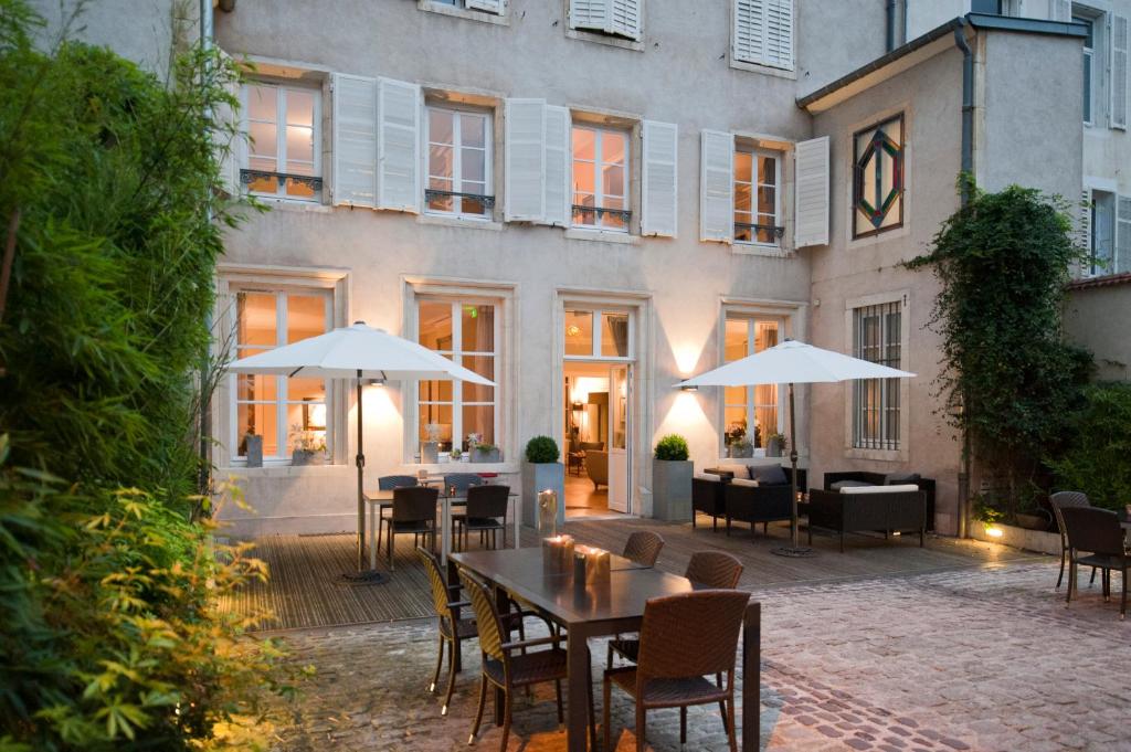 un patio extérieur avec des tables, des chaises et des parasols dans l'établissement Maison d'Hôte de Myon, à Nancy