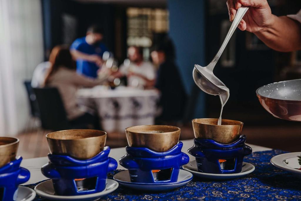 a person is pouring tea into blue cups on a table at Hilton Malta in St Julian's