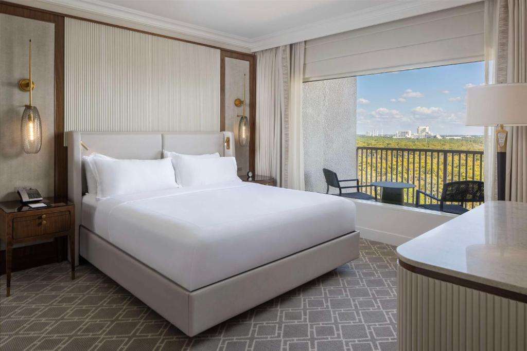 a bedroom with a large white bed and a balcony at Waldorf Astoria Orlando - An Official Walt Disney World Hotel in Orlando