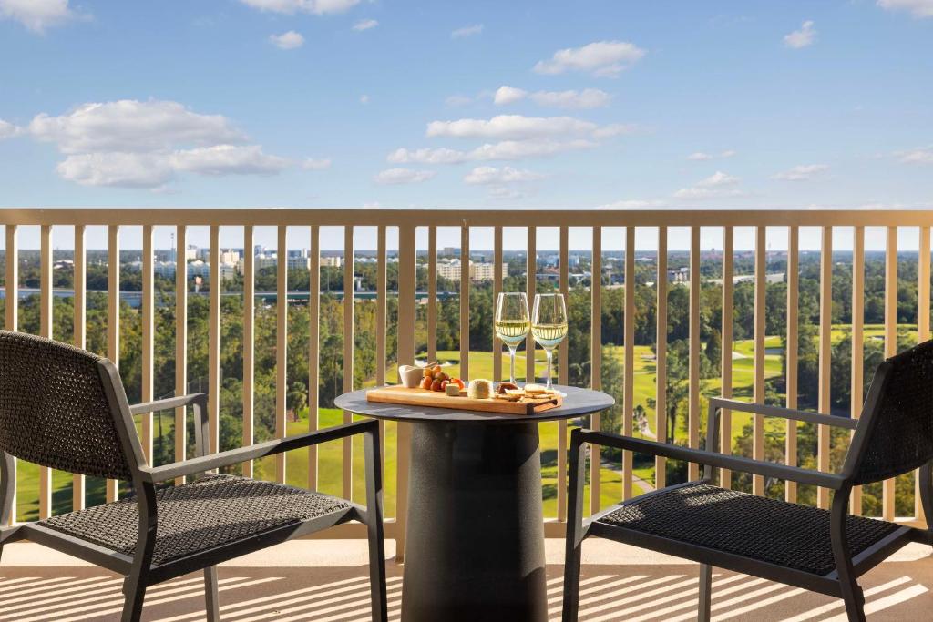 a table and two chairs on a balcony with wine glasses at Waldorf Astoria Orlando - An Official Walt Disney World Hotel in Orlando
